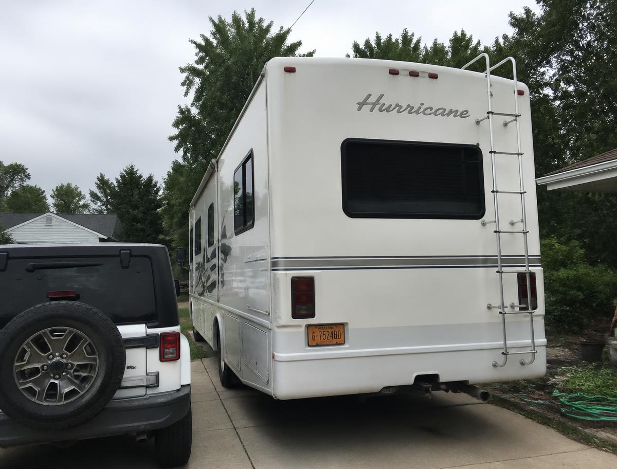 Large motorhome and a Jeep parked in a residential driveway